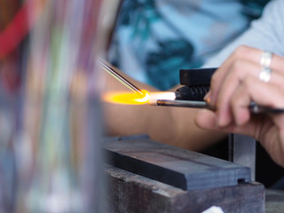 Process Artist of glass at work. A bead is made in the fire.