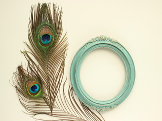 Obraz premium Clothing and home decoration. Beautiful peacock's feathers and elegant vintage frame on white background. Top view with place for text.