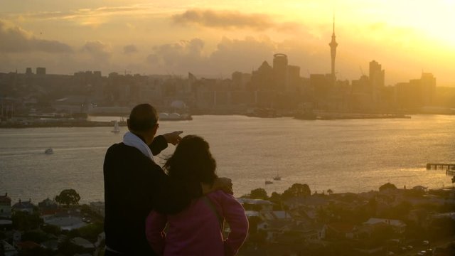 Senior couple watching sunset in Auckland city from mount Victoria in Devonport, Auckland, New Zealand. Sightseeing point, travel attraction in Auckland, New Zealand. Couple travel lifestyle.
