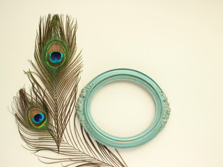 Fototapeta premium Clothing and home decoration. Beautiful peacock's feathers and elegant vintage frame on white background. Top view horizontally with place for text.