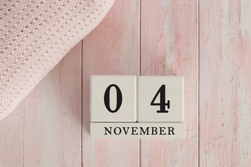4 November Date on Cubes. Date on painted pink wood, next to baby blanket. Theme of baby due dates and birth dates.