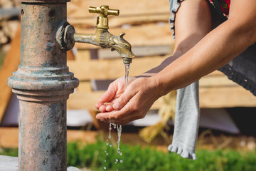 Woman washes her hands under the tap on the street_