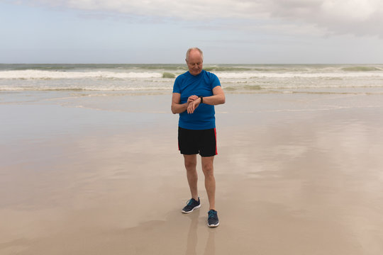 Happy senior man using smartwatch at the beach