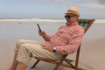 Senior man listening music on mobile phone while relaxing