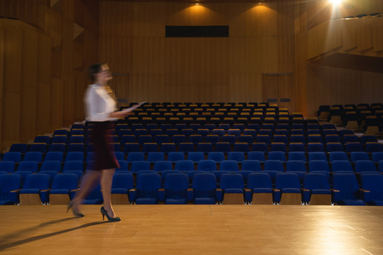 Businesswoman practicing and learning script while walking in the auditorium