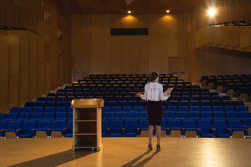 Businesswoman practicing and learning script while standing in the auditorium