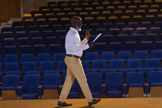  Businessman practicing and learning script while walking in the auditorium