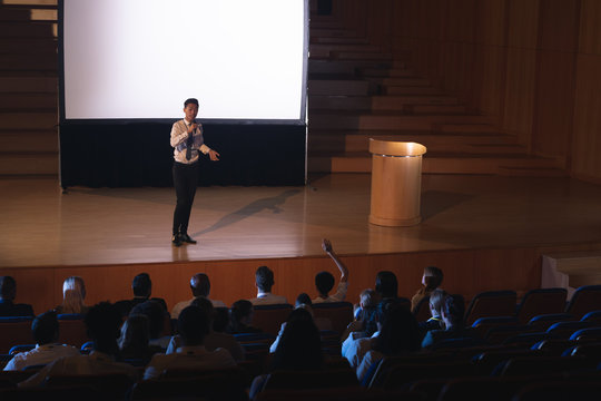 Businessman standing and giving presentation in auditorium 