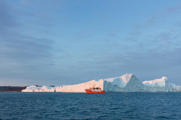 Large iceberg and boat in the Disko Bay, Greenland. The source of these icebergs is the Jakobshavn...
