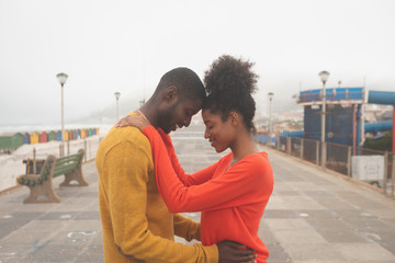 Couple standing on pavement near beach on a sunny day