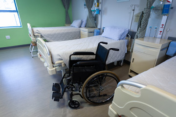 Row of empty hospital beds and wheelchair 