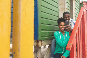 Fototapeta na wymiar Couple taking selfie while sitting near beach hut