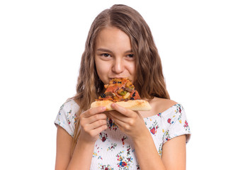 Happy beautiful young teen girl appetizing bites slice of pizza. Close up portrait of child with delicious Italian pizza, isolated on white background. Girl looks at camera and eating fast food.