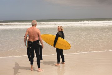 Senior couple holding surfboard on the beach