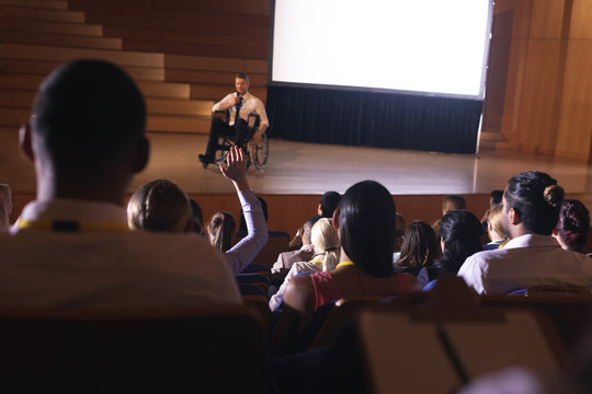 Businessman sitting on a wheelchair and giving presentation to the audience - Powered by Adobe