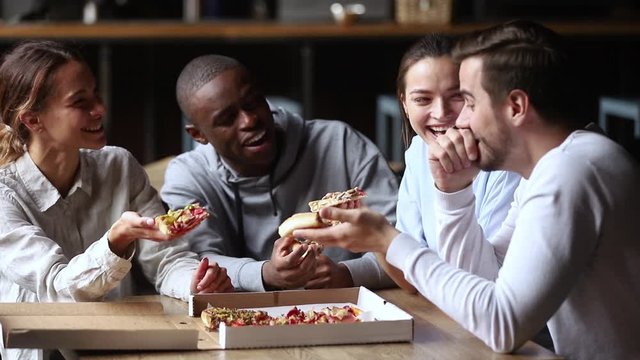 Multi ethnic friends spending time together chatting laughing eating pizza