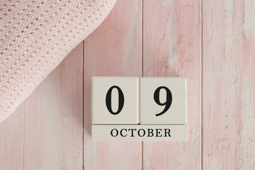 9 October Date on Cubes. Date on painted pink wood, next to baby blanket. Theme of baby due dates and birth dates.