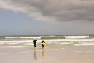 Senior couple walking with surfboard on the beach