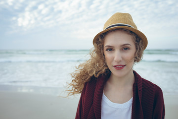 Woman looking and smiling at camera standing on the beach 