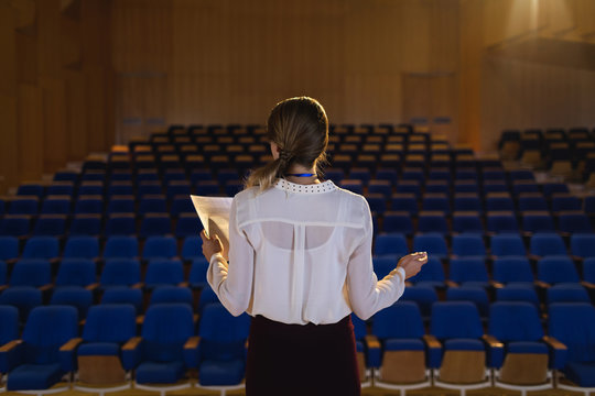 Businesswoman practicing and learning script while standing in the auditorium