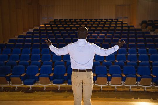 Businessman with arm stretched out standing in a auditorium 