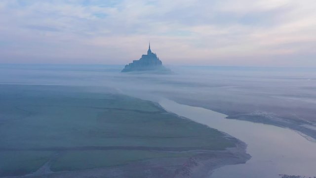 Moody amazing aerial of Mont Saint-Michel France rising out of the mist and fog in early morning.