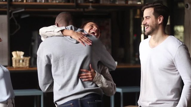 Friends greeting african guy happy to see him at bar