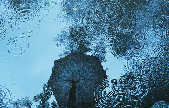 reflection umbrella in puddle background. abstract rain backdrop. autumn season, wet weather, rainy day, fall time concept. soft selective focus