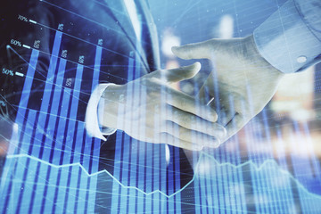 Double exposure of financial chart on cityscape background with two businessmen handshake. Concept of financial analysis and investment opportunities