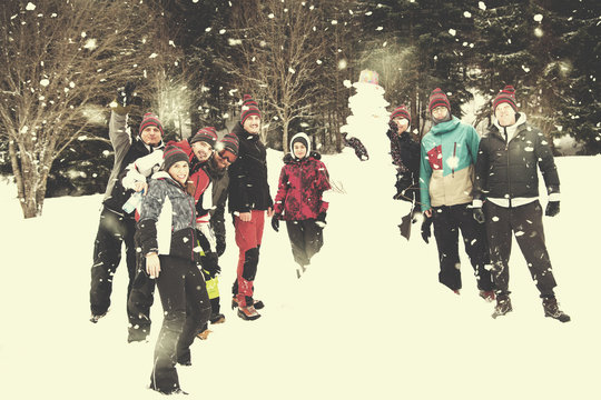 Group Portait Of Young People Posing With Snowman