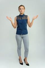 Full length studio portrait of a pretty young woman girl in a business suit on a white background. He stands right in front of the camera, explains, shows his hands with emotions.