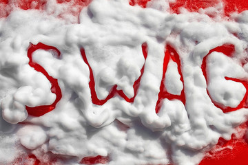 The word SWAG from shaving foam. On a red background. Macro. View from above.