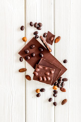 Chocolate with nuts and its ingredients on white wooden background top view