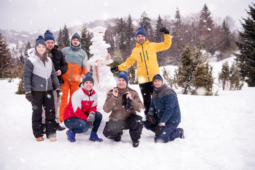 group portait of young people posing with snowman