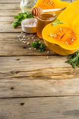 Halves of raw pumpkin butternut squash, with olive oil, spices and ingredients for cooking on rustic old wooden background.Top view copy space. banner