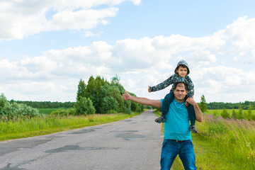 father and son hitchhiking along a road