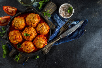 Homemade chicken meatballs in tomato sauce in a frying pan on dark stone or concrete table. Top view copy space