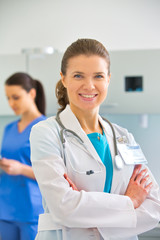 Portrait of confident doctor standing against nurse at clinic