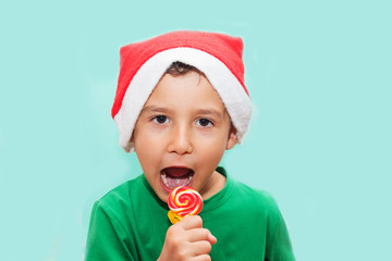 funny boy in Santa's hat eating candy