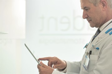 Confident doctor reading medical report on digital tablet at dental clinic