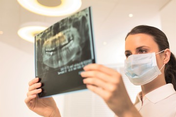Doctor wearing face mask while examining x-ray at ciinic