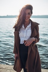 Beautiful Young Stylish Girl in Coat Walking in the Spring Beach at Sunset