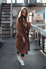 Beautiful Young Stylish Girl in Coat Walking in the Spring Beach at Sunset
