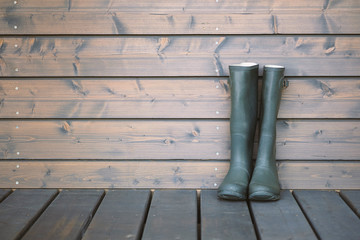 Clean rubber boots on a wooden background. The concept of the garden work.