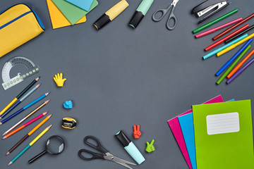 Flat lay photo of workspace desk with school accessories or office supplies on gray background.
