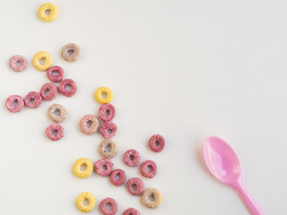 Fruit cereal loops and spoon on white background