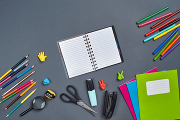 Flat lay photo of workspace desk with school accessories or office supplies on gray background.