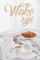 fresh croissant on plate near coffee in white cup on saucer in bed with wake up illustration