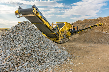 Stone crusher machine in a quarry or open-pit mine, to transform into gravel - obrazy, fototapety, plakaty