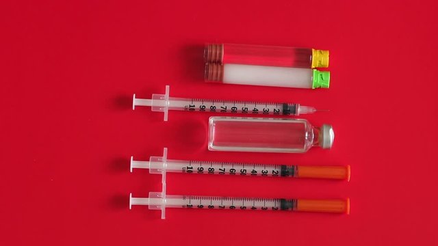 Insulin syringes and insulin of short and prolonged action on a red background, close-up. Concept of immunization, insulin hormone, vaccination, cosmetic injection and health care.